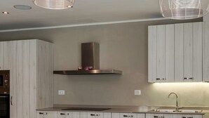 Una cucina moderna con mobili in legno, una cappa in acciaio inossidabile, un'isola centrale con sgabelli e luci a sospensione.