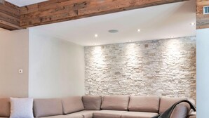 Un soggiorno moderno con una parete in pietra, un soffitto in legno e un camino.