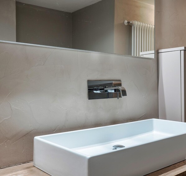 A modern bathroom with a large rectangular sink, a built-in mirror, and a radiator.