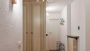 A hallway with a wardrobe, a radiator, and a door with a light switch.