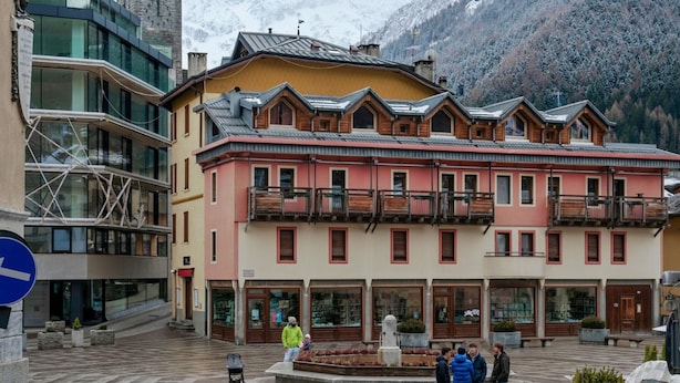 A building with a traditional architectural style, featuring a balcony and a stone tower in the background.