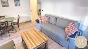 A living room with a sofa, a wooden coffee table, and a dining table with chairs.