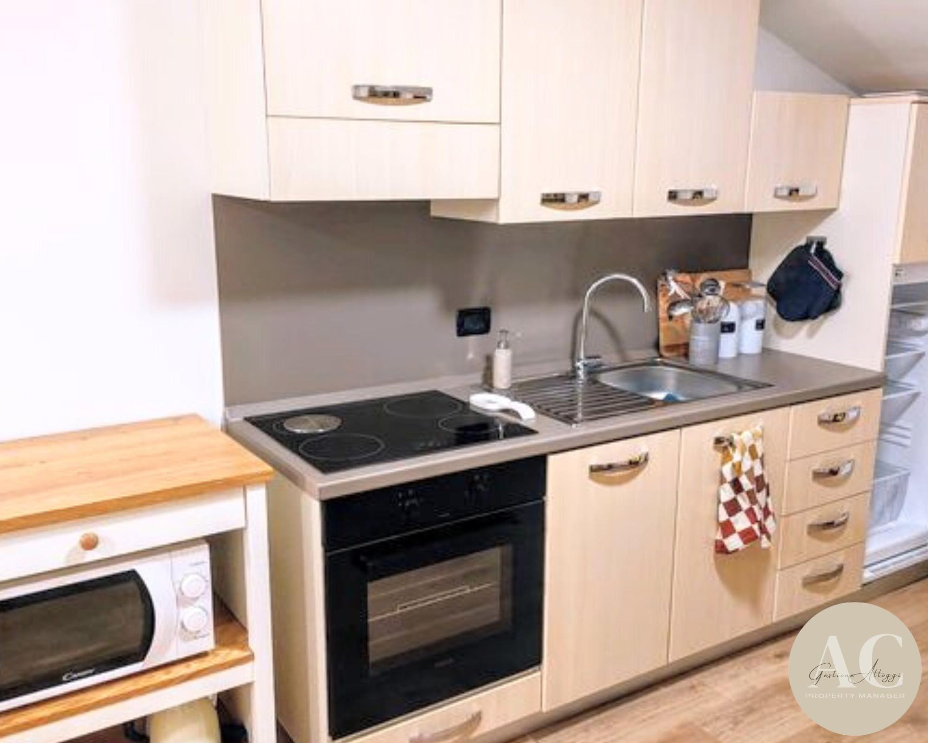 Une cuisine de taille réduite, équipée d’une cuisinière, d’un four, d’un évier et d’un plan de travail en bois.