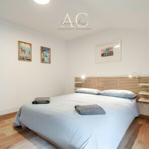 A bedroom with a bed, a nightstand, and two wall-mounted pictures. - Square Apartment in Ponte di Legno (Ponte di Legno)