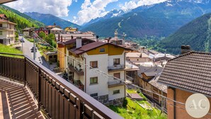 Ein Wohngebiet mit Häusern, einem Balkon und einer Bergkulisse im Hintergrund.