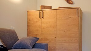 Ein Zimmer mit einem grauen Sofa, einem Holzschrank und Holzboden.