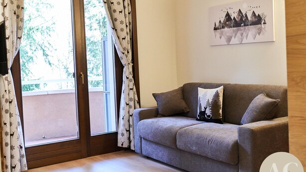 Ein Wohnzimmer mit grauem Sofa, gemusterten Vorhängen und einem gerahmten Bild an der Wand.