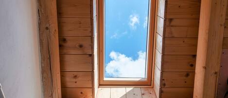 A skylight in a wooden room with a clear blue sky view.