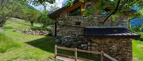 A stone house with a wooden roof and a wooden fence in front.