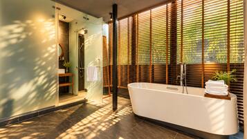 A modern bathroom with a freestanding bathtub, a glass shower enclosure, and a view through wooden blinds.