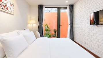 Ein Hotelzimmer mit Bett, Wandfernseher, einem Fenster mit Vorhängen und Blick nach draußen.