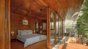 Ein Schlafzimmer einer Holzhütte mit einem Bett, Nachttischen und einem Esstisch.