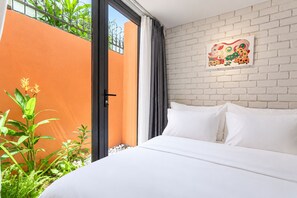A hotel room with a large bed, a brick wall, and a window with curtains. - Nexus House Thao Dien (Ho Chi Minh City)