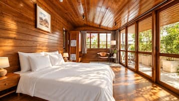 Un dormitorio con techo de madera, una cama grande, una mesita de noche, una silla y una ventana con vista a follaje.