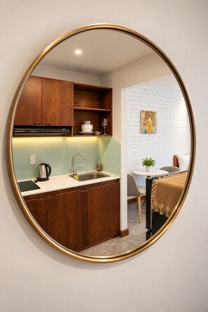 A kitchen with wooden cabinets, a stainless steel sink, and a black kettle. - Nexus House Thao Dien (Ho Chi Minh City)