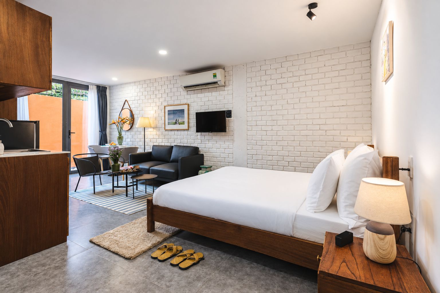 Habitació d'hotel moderna amb llit, escriptori, cadira, sofà i televisió.