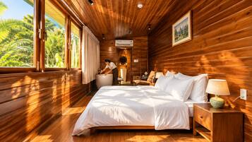 A wooden cabin bedroom with a large bed, a nightstand, a lamp, and a view of the outdoors.