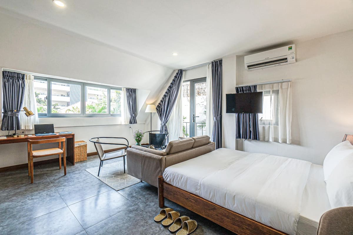 A hotel room with a bed, desk, chair, and a TV.
