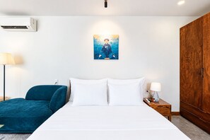 A bedroom with a bed, a blue chair, a wooden wardrobe, and a wall-mounted air conditioner. - Nexus House Thao Dien (Ho Chi Minh City)
