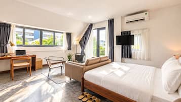 A modern hotel room with a bed, desk, chair, and a TV.