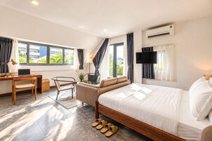 A modern hotel room with a bed, desk, chair, and a TV.