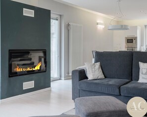 Un soggiorno moderno con camino, un divano grigio e un'area pranzo con forno a microonde.