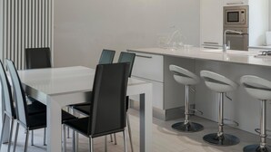 Una cocina moderna con encimera blanca, electrodomésticos de acero inoxidable y una barra con taburetes.