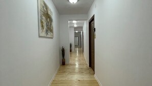 Un pasillo con suelo de madera, paredes blancas y una lámpara en el techo.