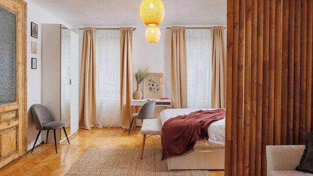 A bedroom with a bed, a desk, a chair, and a wooden partition. - Lunga 16 Guesthouse in City Center (Brașov)