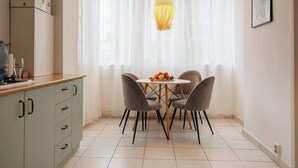 A small dining area with a round table, four chairs, and a hanging light fixture. - Lunga 16 Guesthouse in City Center (Brașov)