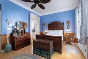 A bedroom with a wooden bed, dresser, and a ceiling fan. There are two vintage suitcases in front of the bed. - Bridges Cottage - Vintage in Heart of Cedar Key! (Cedar Key)