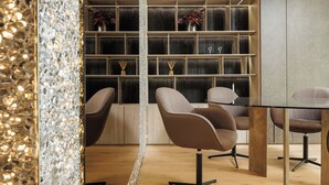 A modern interior with a glass table, brown chairs, and a wooden bookshelf.