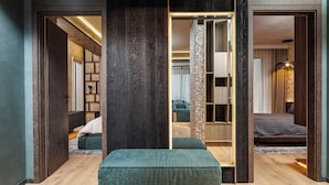 A modern bedroom with a wooden floor, a green sofa, a bed, and a wardrobe with a mirror.
