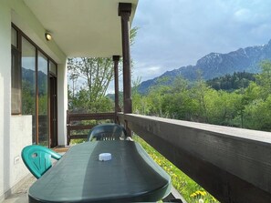 A balcony with a table, chairs, and a view of mountains. - Cozy Riverfront 1 with Garden and Mountain View (Bușteni)