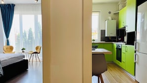 Una cocina moderna con armarios verdes, un refrigerador blanco y una zona de comedor con sillas amarillas.