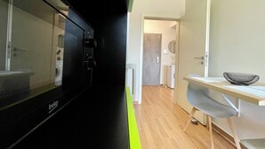 Una cocina moderna con un electrodoméstico negro, una mesa de madera con un cuenco y vistas al baño.