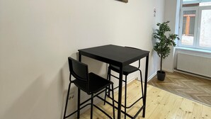 Una habitación con una mesa y sillas negras, una planta en maceta y tres obras de arte con motivos de café.