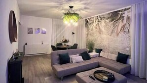A modern living room with a sectional sofa, a coffee table, and a dining area in the background. - Scandiland Apartment (Brașov)
