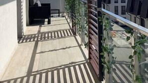 A balcony with a sofa, a railing, and a view of buildings and mountains. - Scandiland Apartment (Brașov)