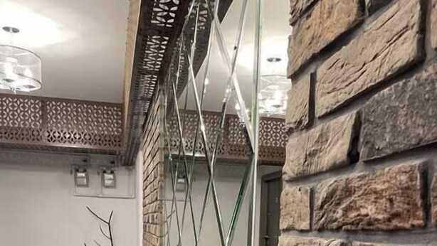A lobby with a stone wall, a glass partition, and a potted plant.