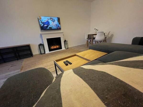 A living room with a fireplace, a TV mounted above it, a sofa, and a coffee table.
