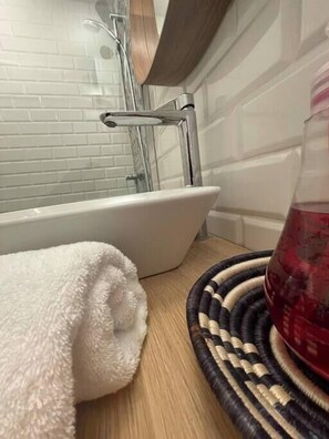A bathroom with a white bathtub, a glass shower enclosure, and a wooden vanity.