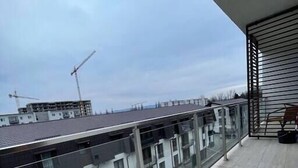 A balcony with a view of surrounding buildings and a construction crane in the distance.