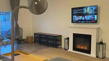 Ein modernes Wohnzimmer mit Kamin, einem an der Wand befestigten Fernseher und einer Stehlampe.