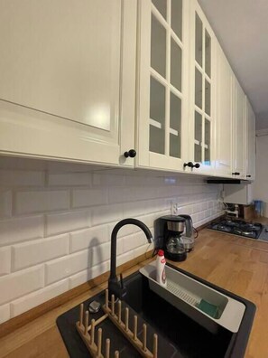 A kitchen with white cabinets, a black faucet, a coffee maker, and a stove.