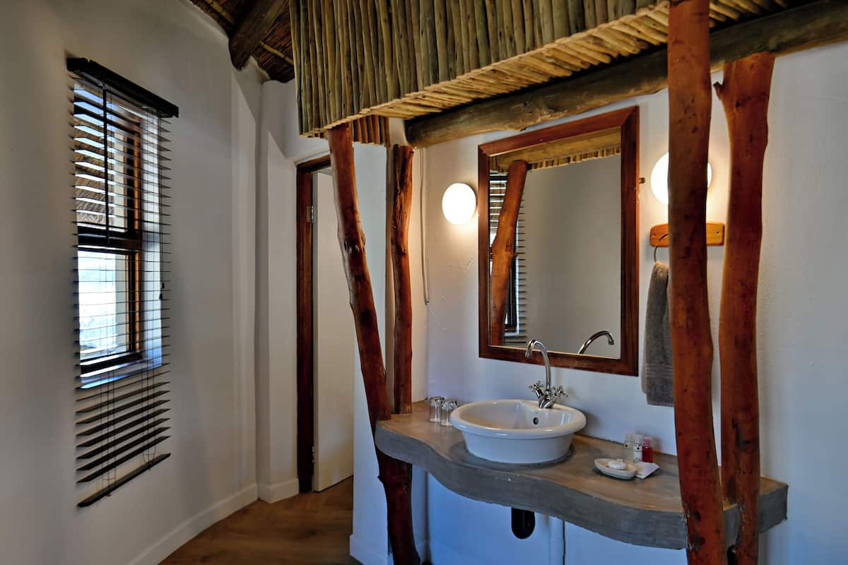A bathroom with a wooden vanity, a white sink, and a mirror.