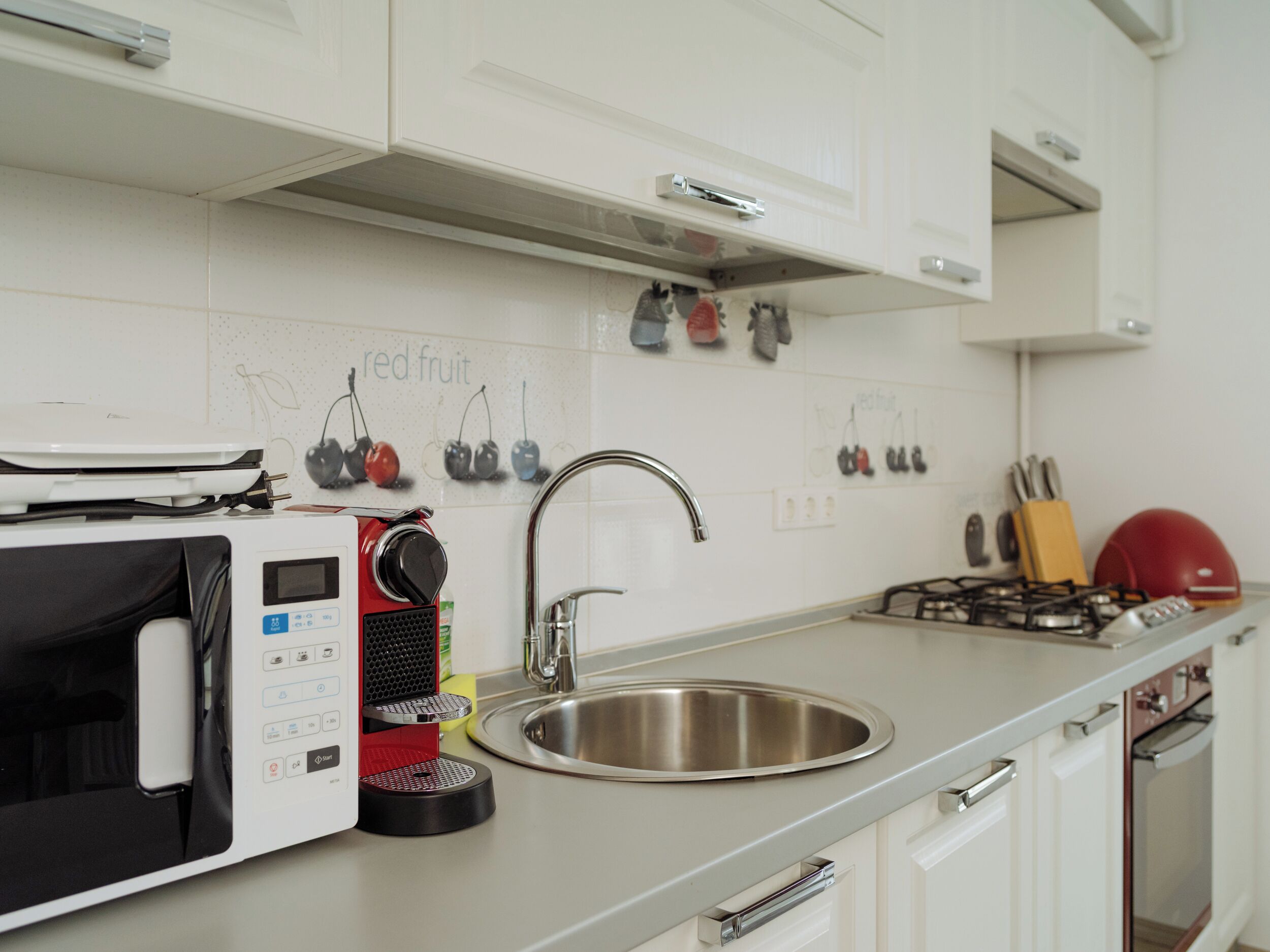 Una cocina equipada con microondas, cafetera, lavabo y estufa.