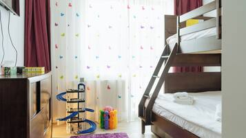 A bunk bed room with a desk, a radiator, and a window with butterfly curtains.
