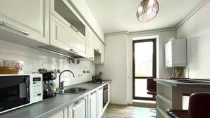 Una cocina moderna con armarios blancos, un lavamanos de acero inoxidable y un microondas.
