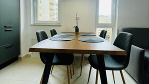 A modern dining area with a wooden table, black chairs, and a pendant light.